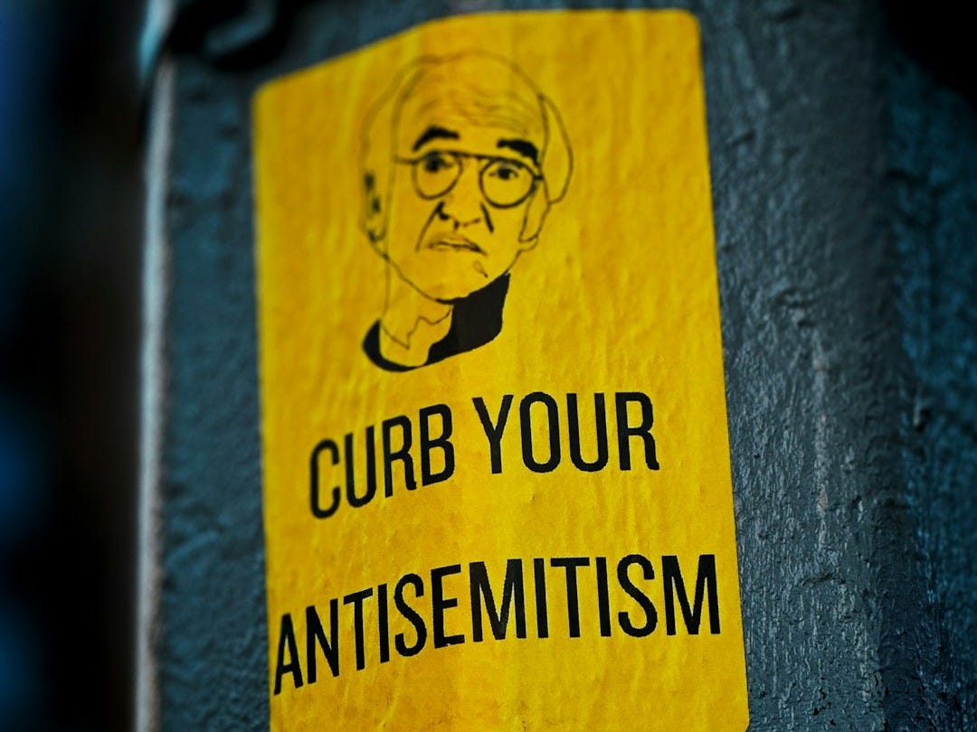 a sticker on the side of a pole that says curb your antisemit