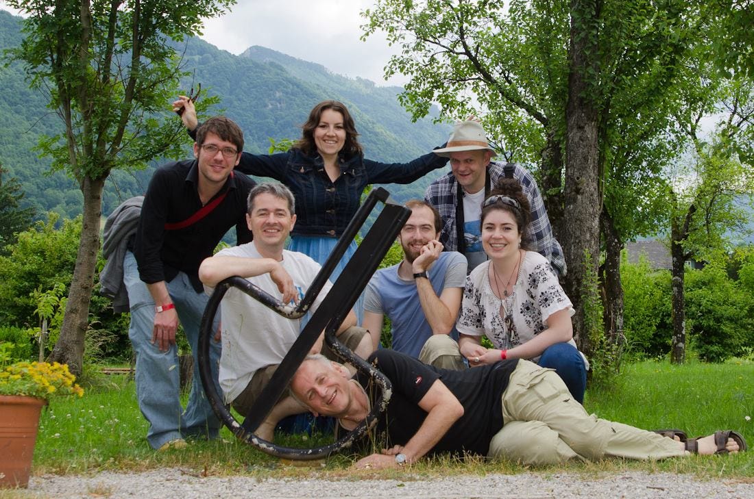 a group of smiling jaw harp players poses around a Maultrommel sculpture in Austria