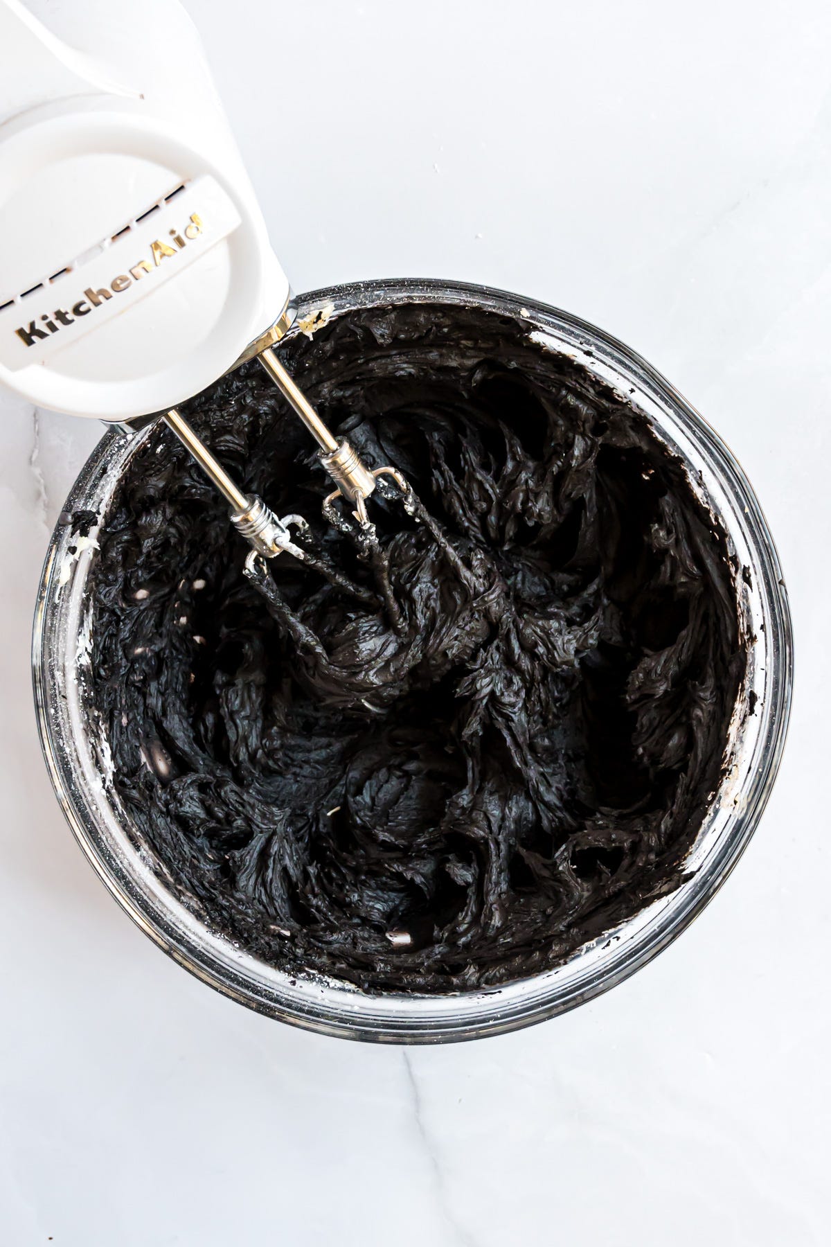 The black frosting in a bowl with beaters.