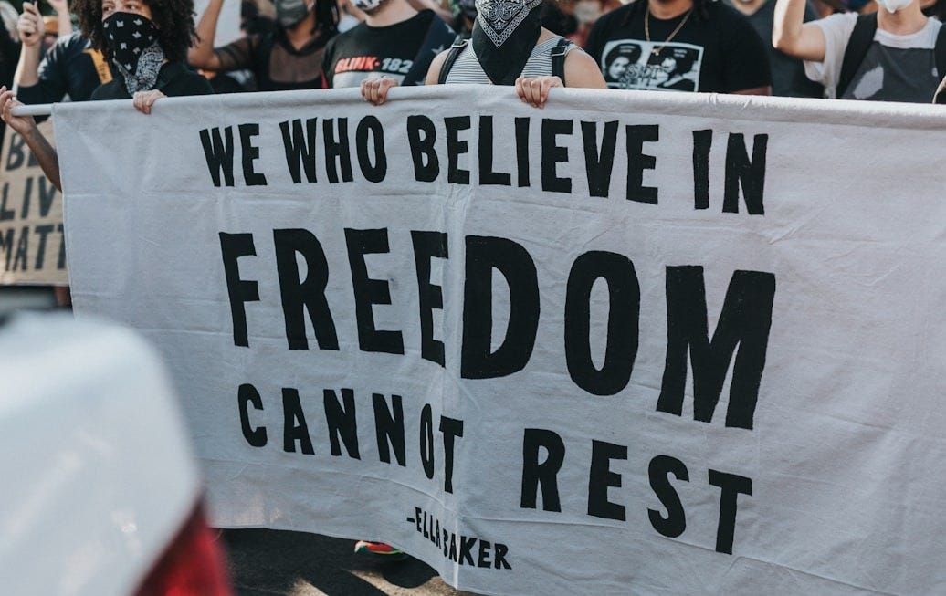 a group of people holding a sign that says we who believe in freedom can ' a group of people holding a sign that says we who believe in freedom can '