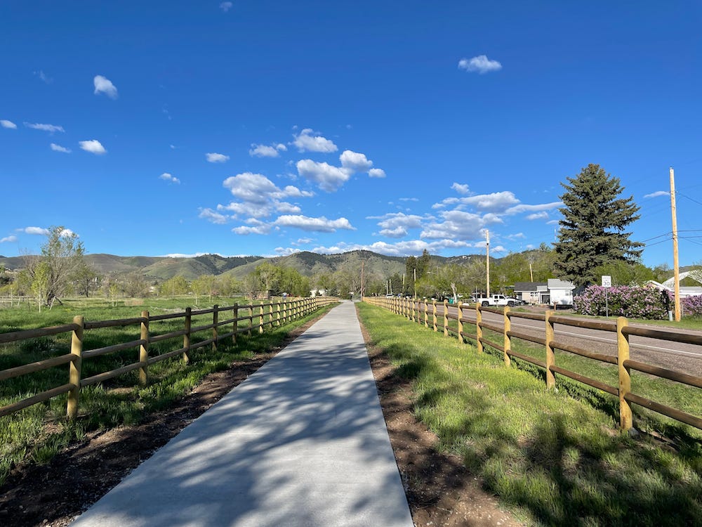 sidewalk stretches out away from camera between two split rail fence lines on a sunny day sidewalk stretches out away from camera between two split rail fence lines on a sunny day