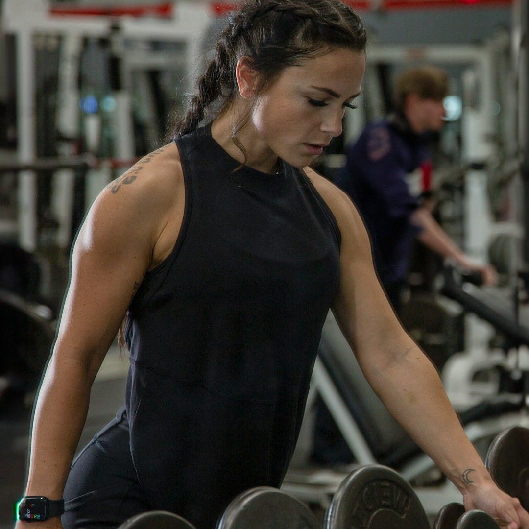 a woman working out with a barbell in a gym