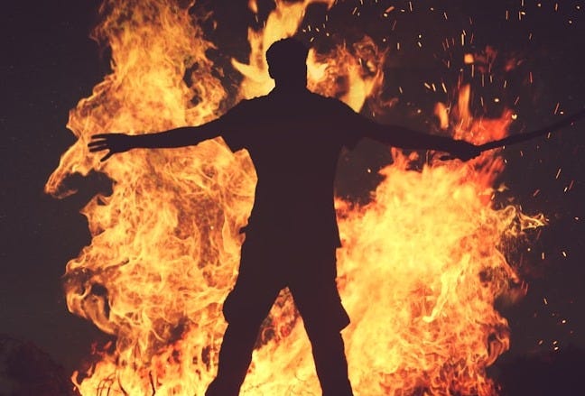 person standing in front of fire during night time person standing in front of fire during night time
