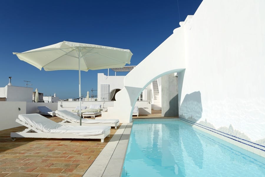 Sonnenliegen mit kleinem Pool und Sonnenschirm bei blauem Himmel. Bild von Local Hideaways