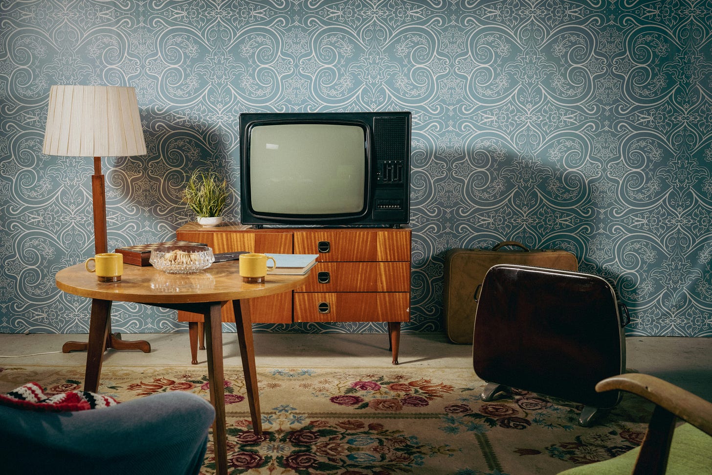 A midcentury modern living room featuring a TV on a media stand, a lamp, a coffee table, and some chairs