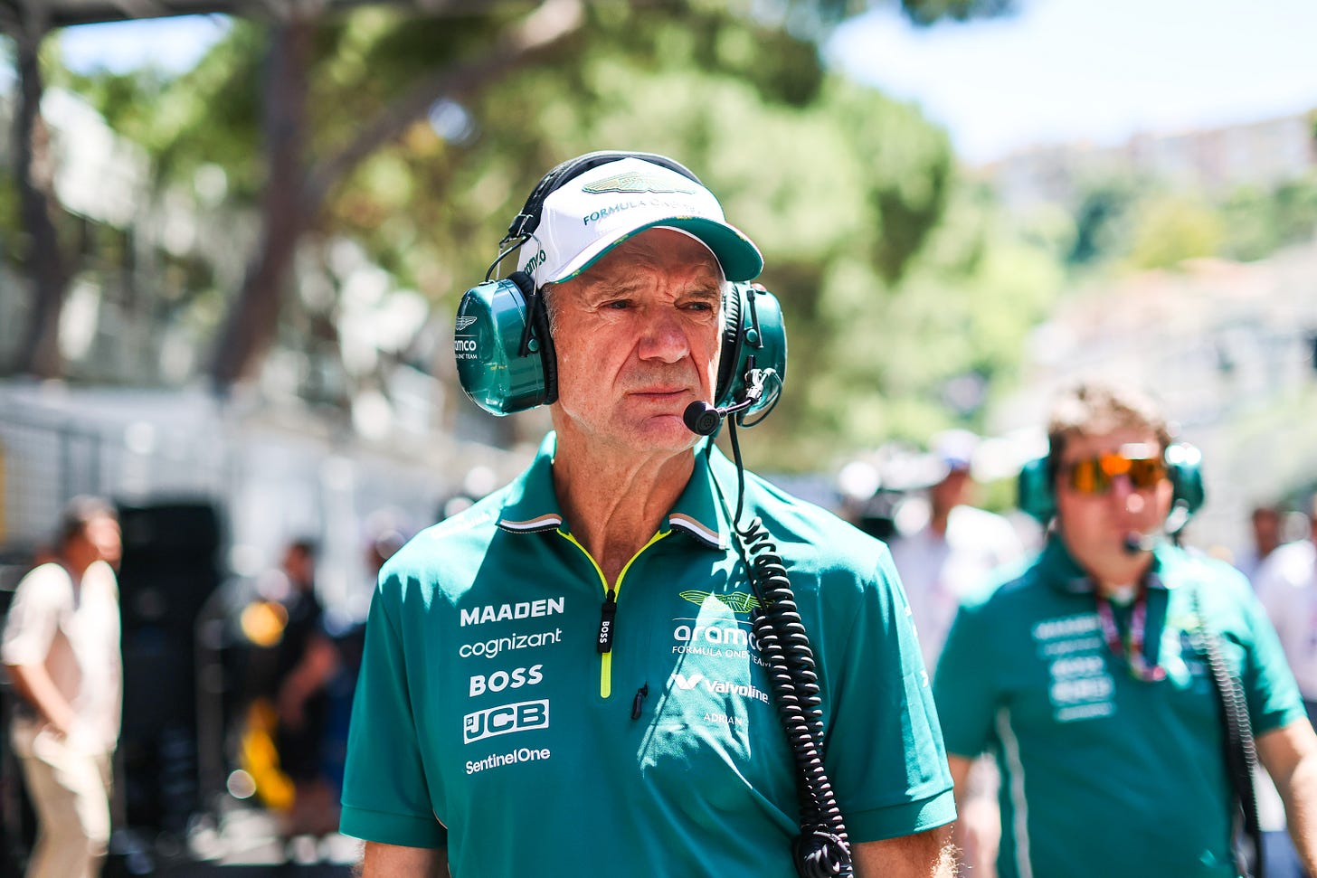 Adrian Newey wearing Aston Martin teamwear and giant green headphones on the F1 grid