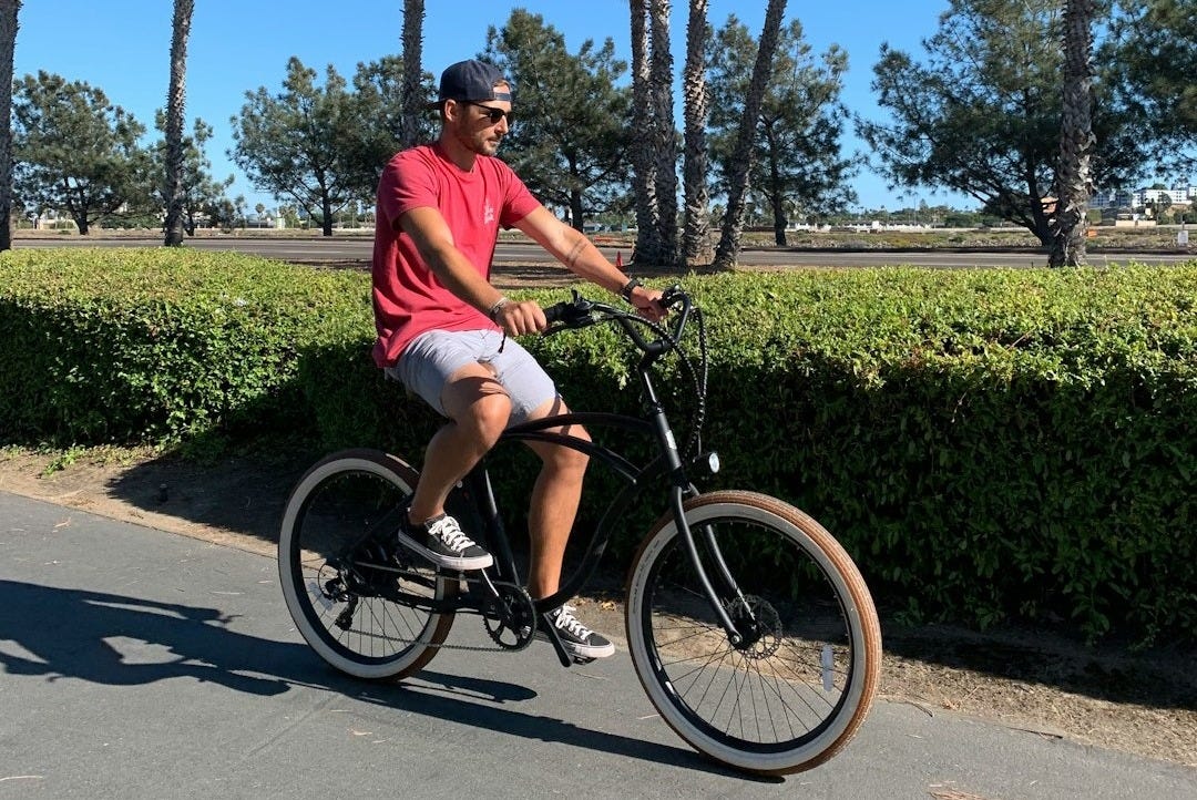 man riding beach cruiser near hedges and palm trees man riding beach cruiser near hedges and palm trees