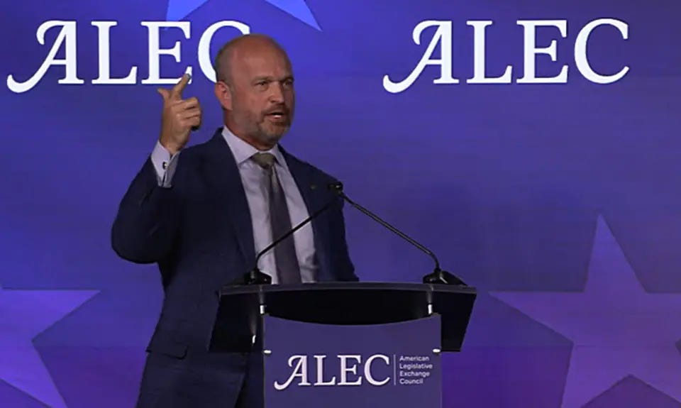 Heritage Foundation President Kevin Roberts, a bald white man wearing suit and tie, gestures with his right hand while speaking behind a lectern bearing the ALEC logo, which is also repeated on the background. Heritage Foundation President Kevin Roberts, a bald white man wearing suit and tie, gestures with his right hand while speaking behind a lectern bearing the ALEC logo, which is also repeated on the background.