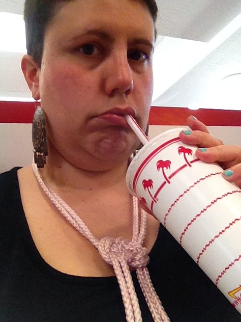 Lauren making sad and disgusted faces while sipping a soda at an In-N-Out circa 2015.