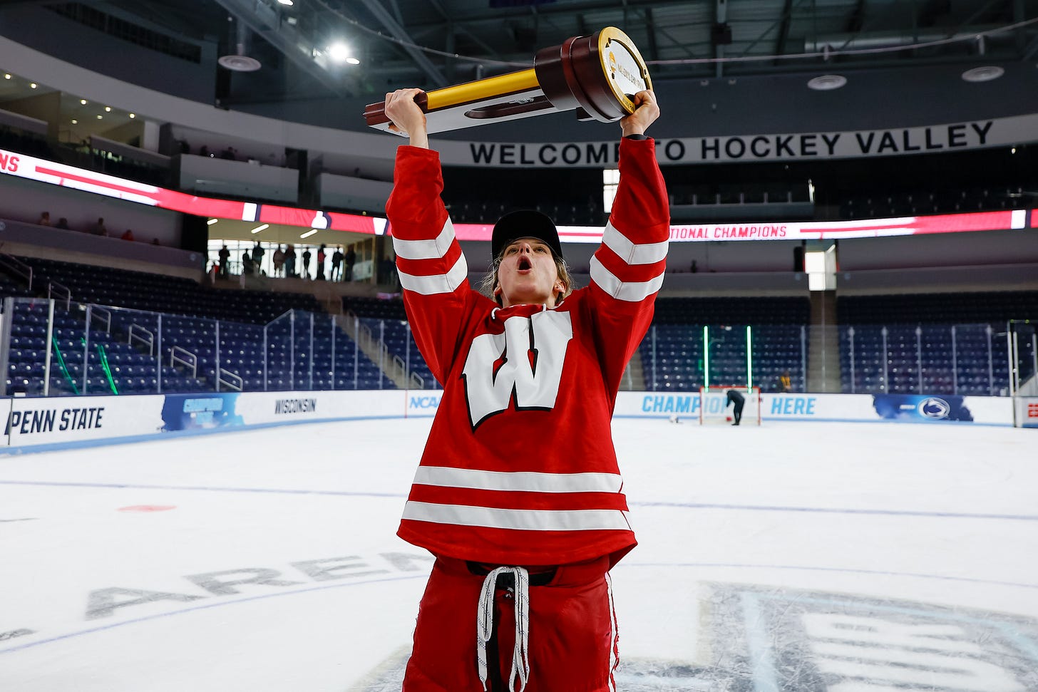 Lacey Eden shouts while lifting a trophy above her head with both hands