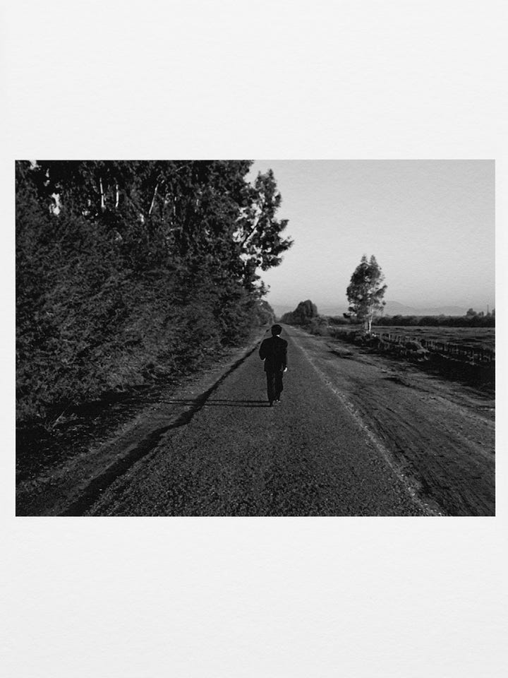Two black-and-white stills from Shirin Neshat’s Fervor showing a man and a woman walking alone on separate roads, emphasizing distance, restraint, and tension.
