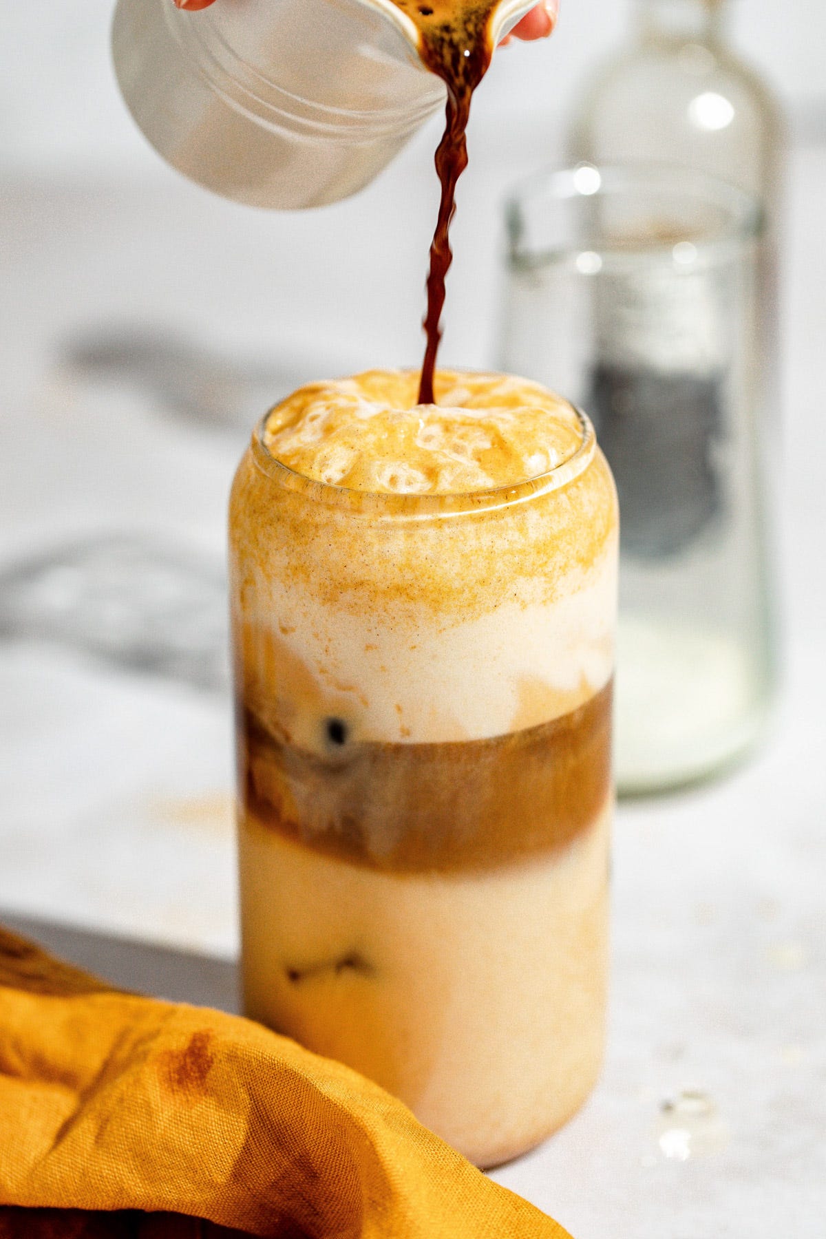 Espresso being poured into the glass with the pumpkin spice milk.