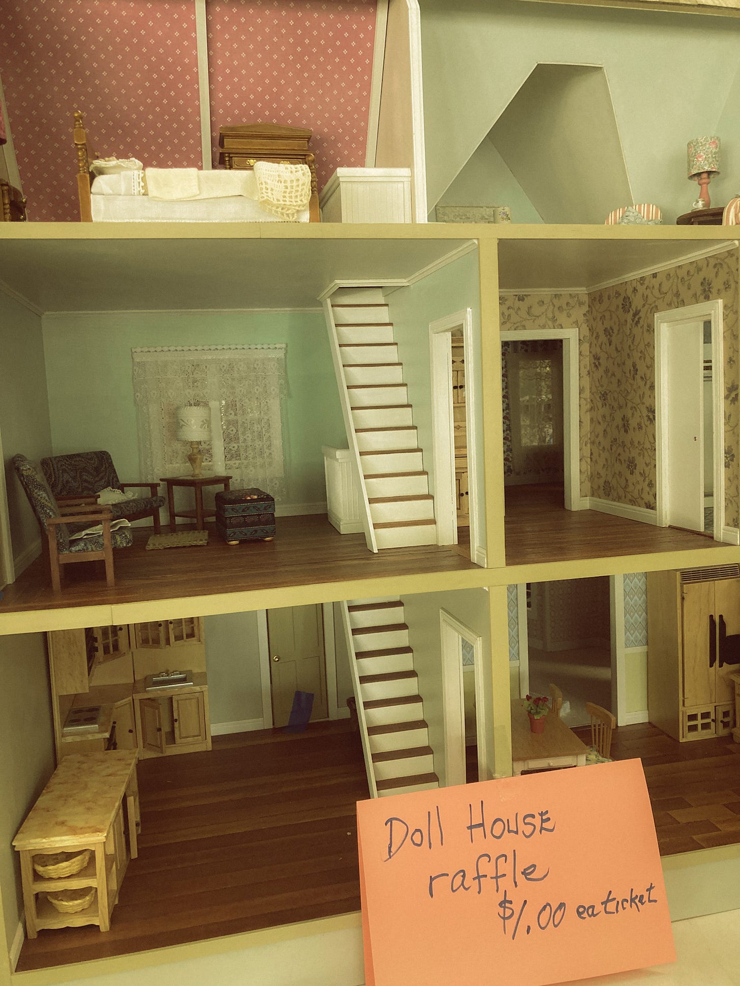 A dollhouse at a thrift store with a handwritten sign: "dollhouse raffle $1 each ticket"