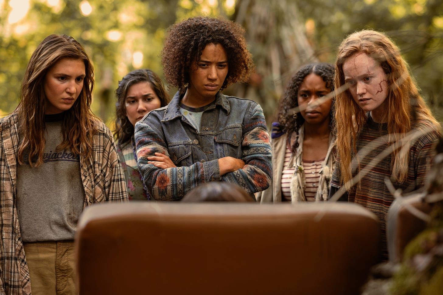 Sophie Nélisse as Teen Shauna, Vanessa Prasad as Teen Gen, Jasmin Savoy Brown as Teen Taissa, Silvana Estifanos as Teen Britt, and Liv Hewson as Teen Van in a production still from the third season of the Showtime survivalist drama “Yellowjackets.” They are wearing tattered clothes and staring at a mysterious object in the woods. Sophie Nélisse as Teen Shauna, Vanessa Prasad as Teen Gen, Jasmin Savoy Brown as Teen Taissa, Silvana Estifanos as Teen Britt, and Liv Hewson as Teen Van in a production still from the third season of the Showtime survivalist drama “Yellowjackets.” They are wearing tattered clothes and staring at a mysterious object in the woods.