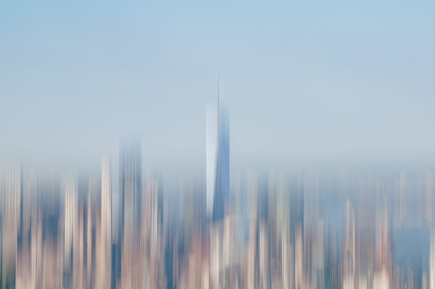The downtown skyline pulled into fine vertical streaks by a moving camera, one tall tower still readable as a pale shaft against blue. The downtown skyline pulled into fine vertical streaks by a moving camera, one tall tower still readable as a pale shaft against blue.