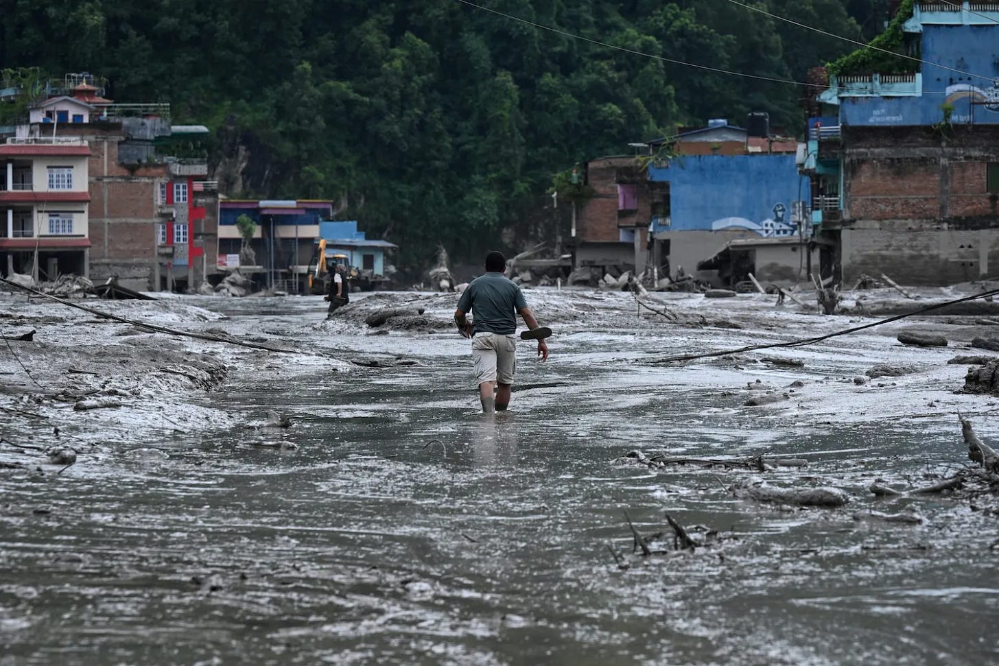 A resident walks along a street covered in mud following flash floods and a landslide disaster in Nepal. A resident walks along a street covered in mud following flash floods and a landslide disaster in Nepal.