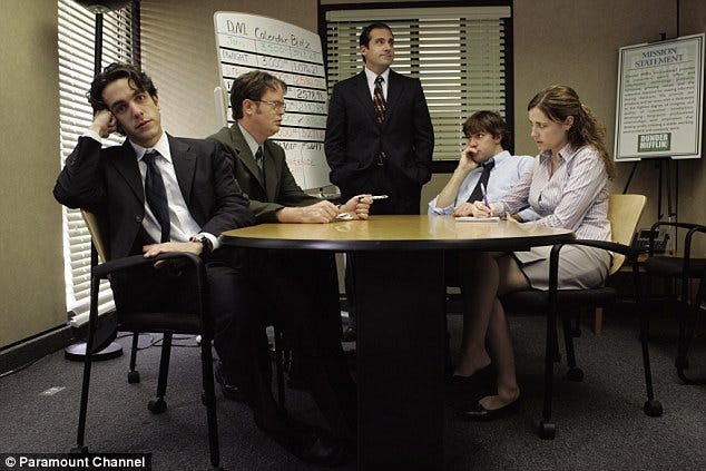Ryan, Dwight, Michael, Jim, and Pam sit around a conference table.