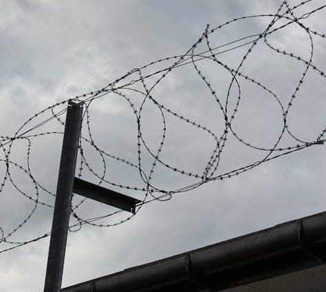 a barbwire fence with a cloudy sky in the background