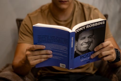 Free Close-up of a person reading 'Poder Sem Limites' by Tony Robbins indoors. Stock Photo
