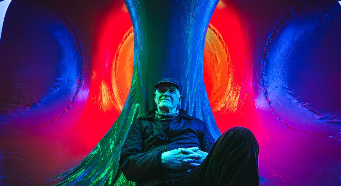 A man - Alan Parkinson - leaning against an inflatable pillar, with colourful tunnels behind him