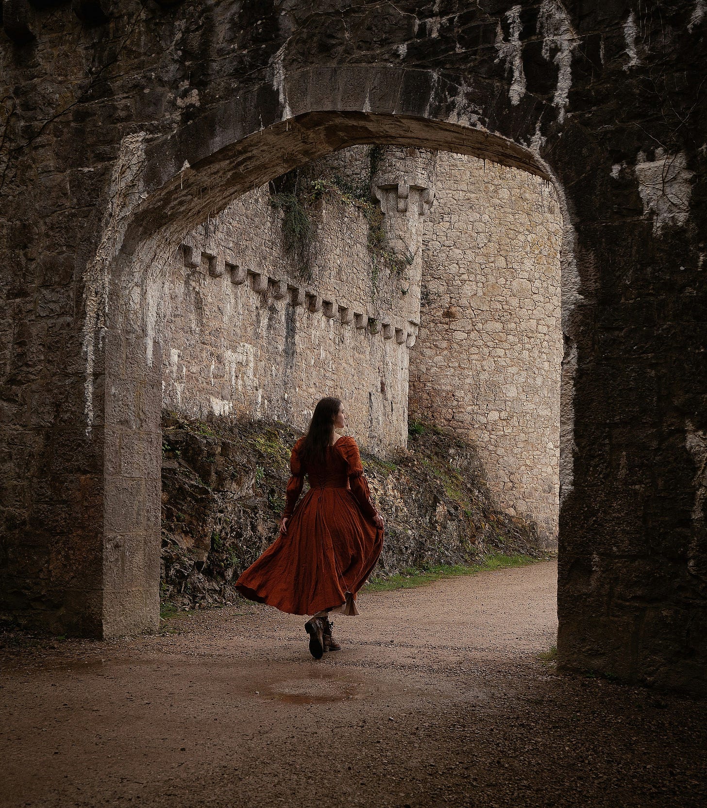 a-woman-in-a-red-dress-is-walking-through-a-tunnel