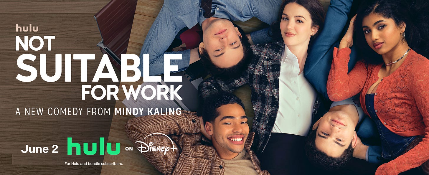 The cast of Not Suitable for Work are lying on a table looking up at a camera. They're grouped together.