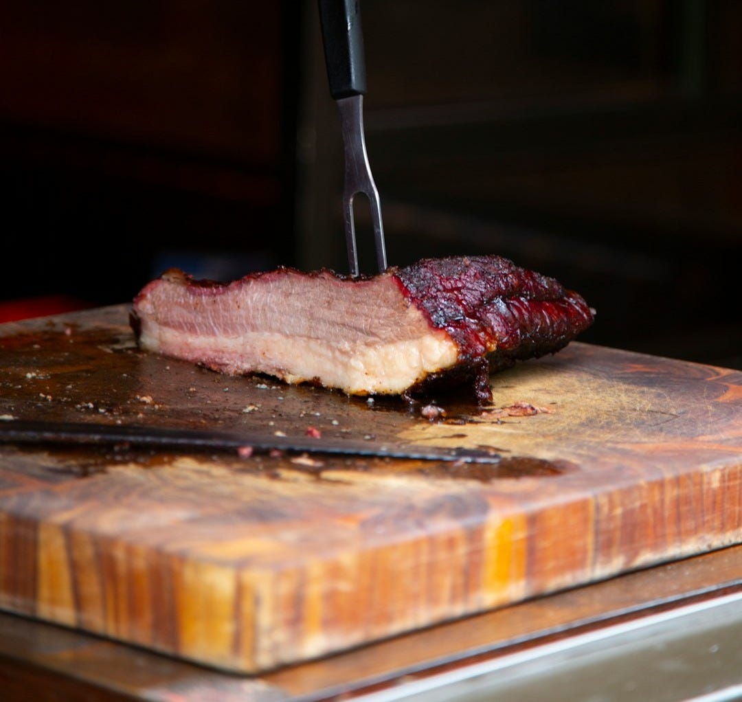 a piece of meat on a cutting board with a knife a piece of meat on a cutting board with a knife