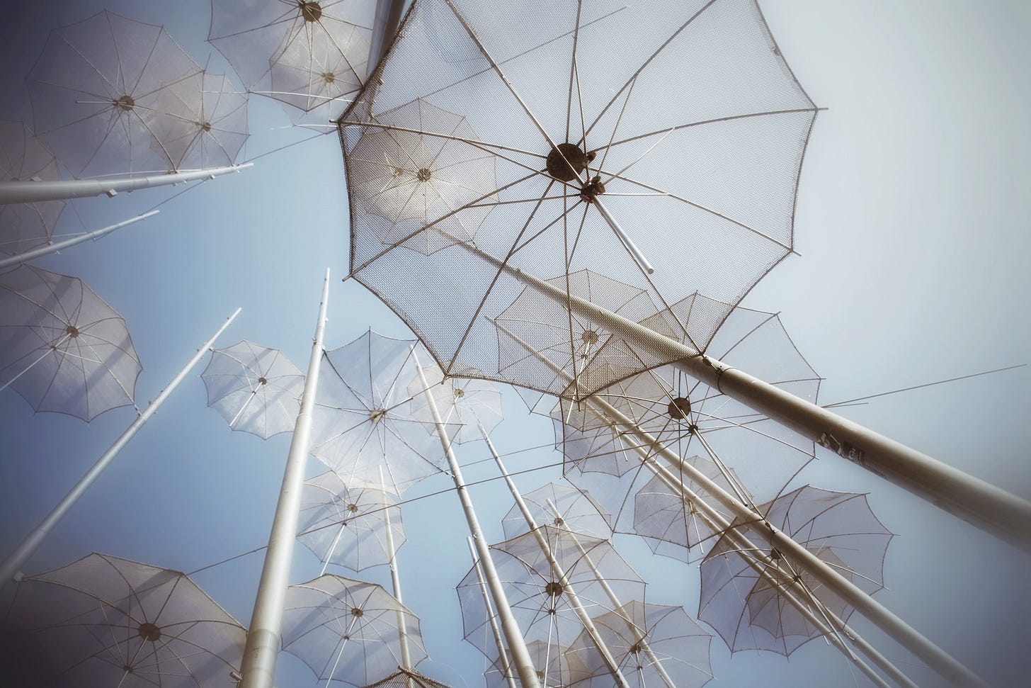 Geometric installation of white umbrellas against blue sky in Thessaloniki, shot from below - the photograph referenced in essay about choosing permanence over digital performance
