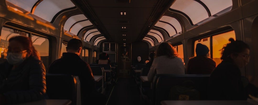 a group of people sitting on a train next to each other a group of people sitting on a train next to each other