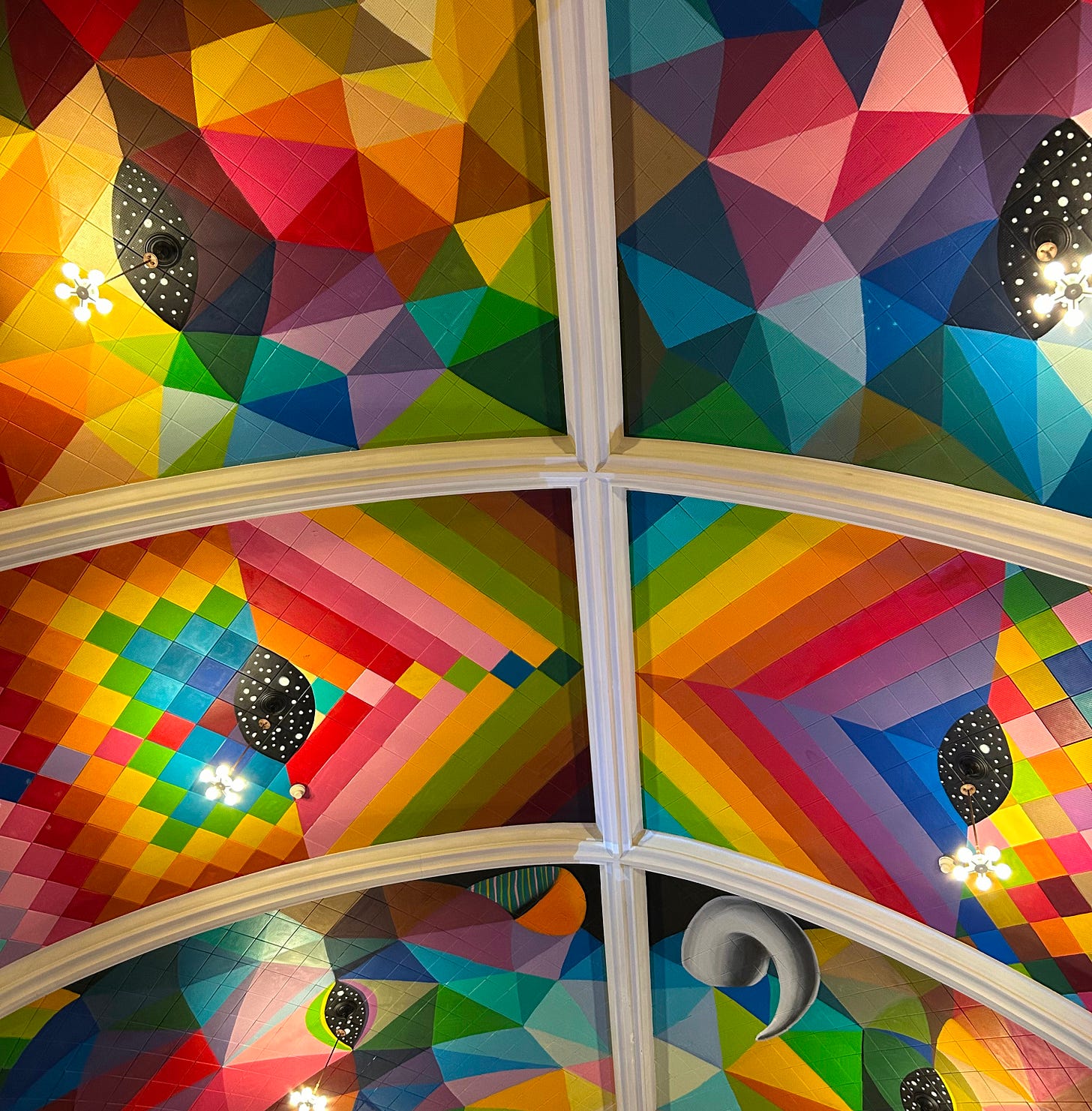 6 panels of a church ceiling, all with multicolored geometric shapes, some that create a perspective and three dimensions