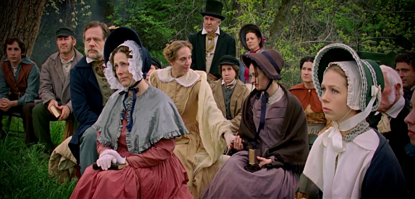 Congregation of pioneer saints with Emma Smith sitting next to a woman in a yellow dress