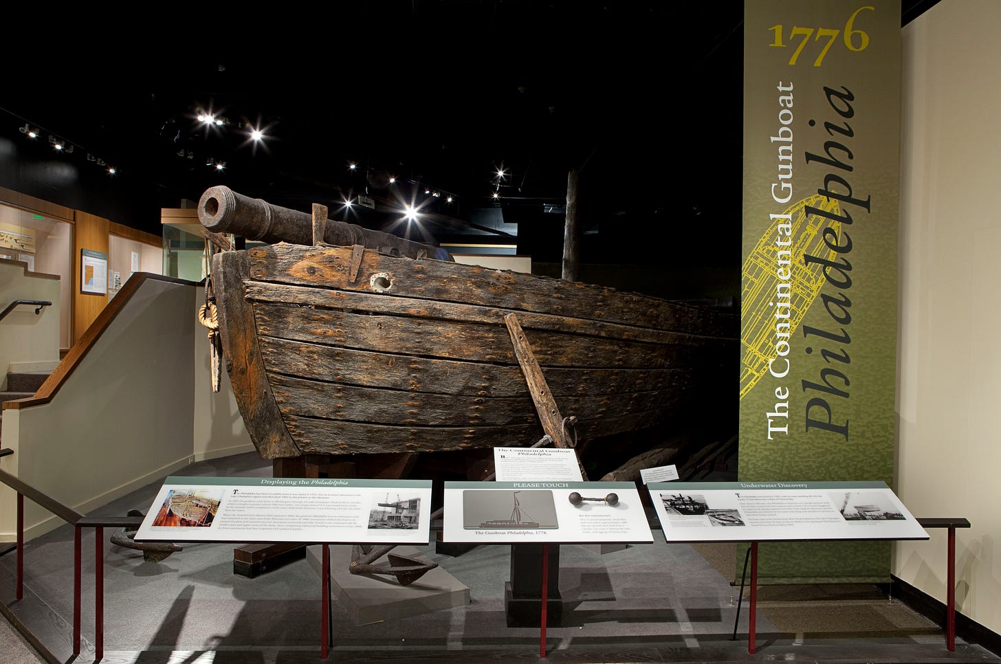 The gunboat Philadelphia, with its forward cannon, sits at the center of an exhibition space