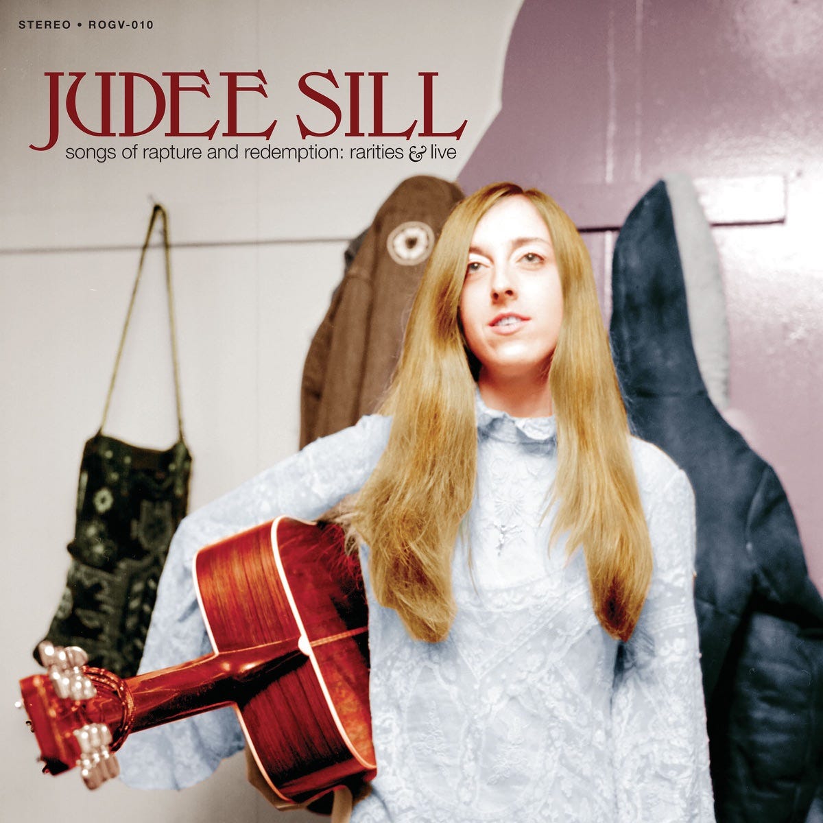 Judee Sill, holding a guitar under her arm, on an album cover