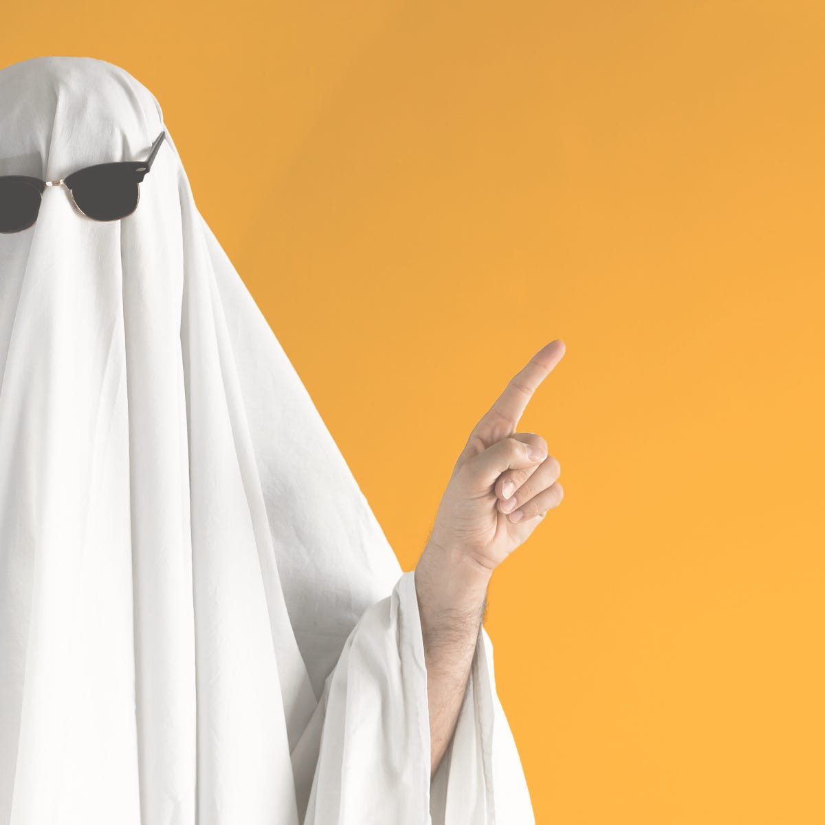 Person dressed as a ghost with sunglasses pointing upward against a bright orange background—representing content that lacks structure and presence.
