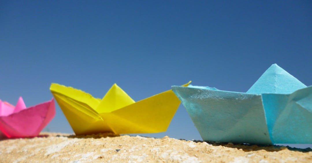 three origami boats sitting on top of a rock three origami boats sitting on top of a rock