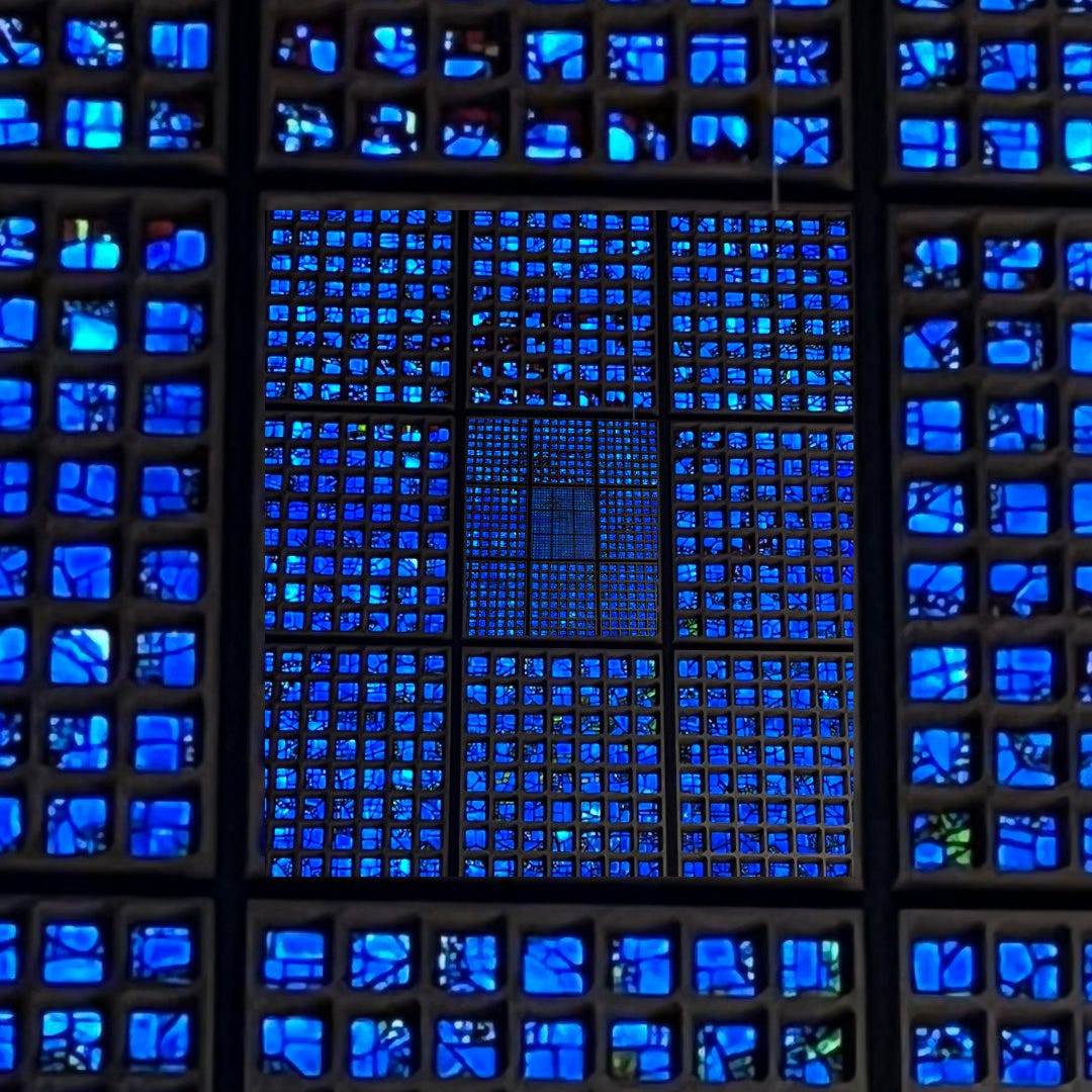Photo illustration of a wall of blue stained glass squares, assembled into a square, which seemingly repeat into smaller and smaller iterations of itself, into infinity.