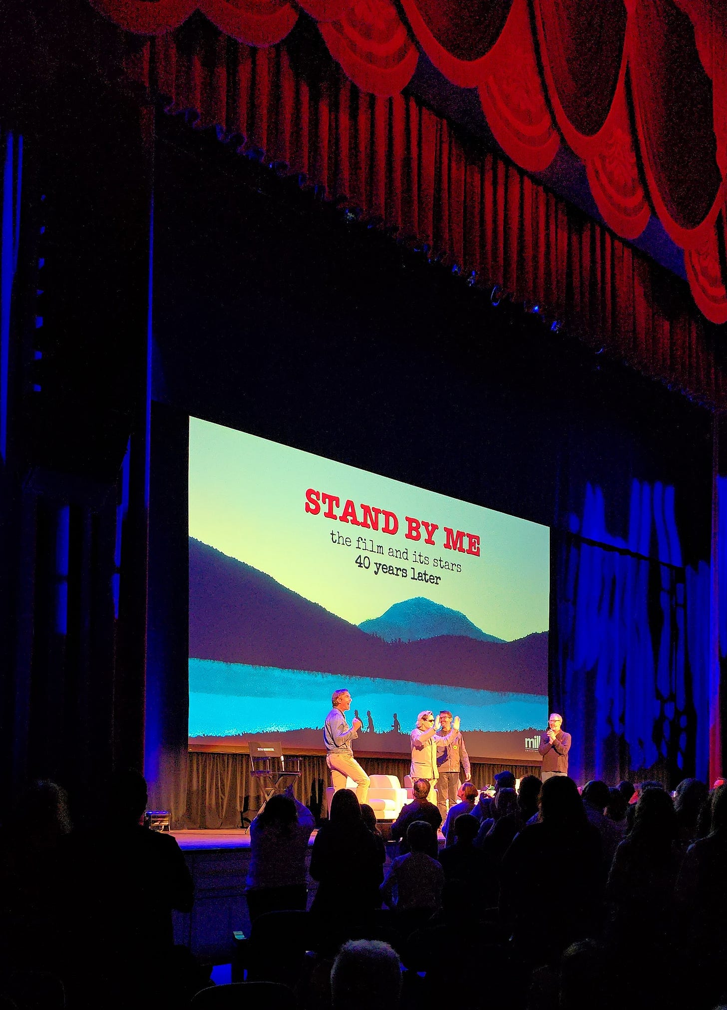 The stars of the movie Stand By Me: Corey Feldman, Jerry O'Connell, and Wil Wheaton, greeting the audience on stage, with a red curtain draped above their heads