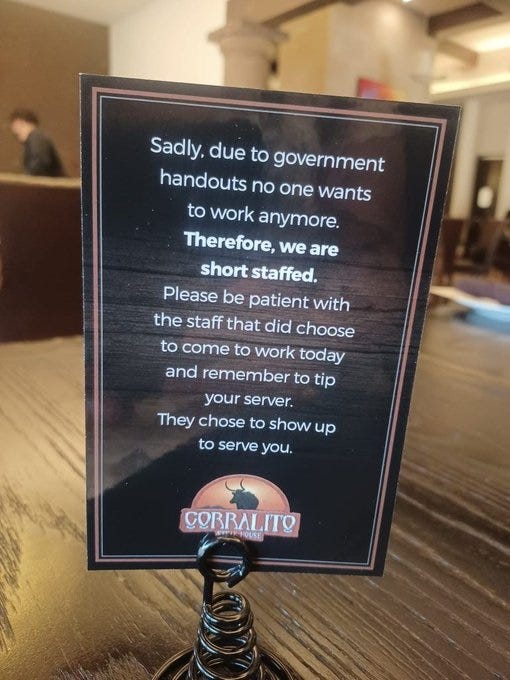 Photo of a placard on a table in a restaurant: 'Sadly, due to government handouts, no one wants to work anymore. [in boldface:] Therefore, we are short staffed. [Regular text resumes:] Please be patient with the staff that did choose to come to work today and remember to tip your server. They chose to show up to serve you.'