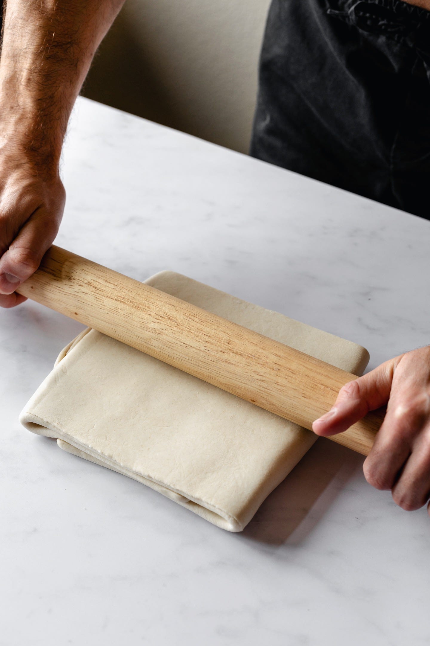 Rolling vegan puff pastry dough on a white counter