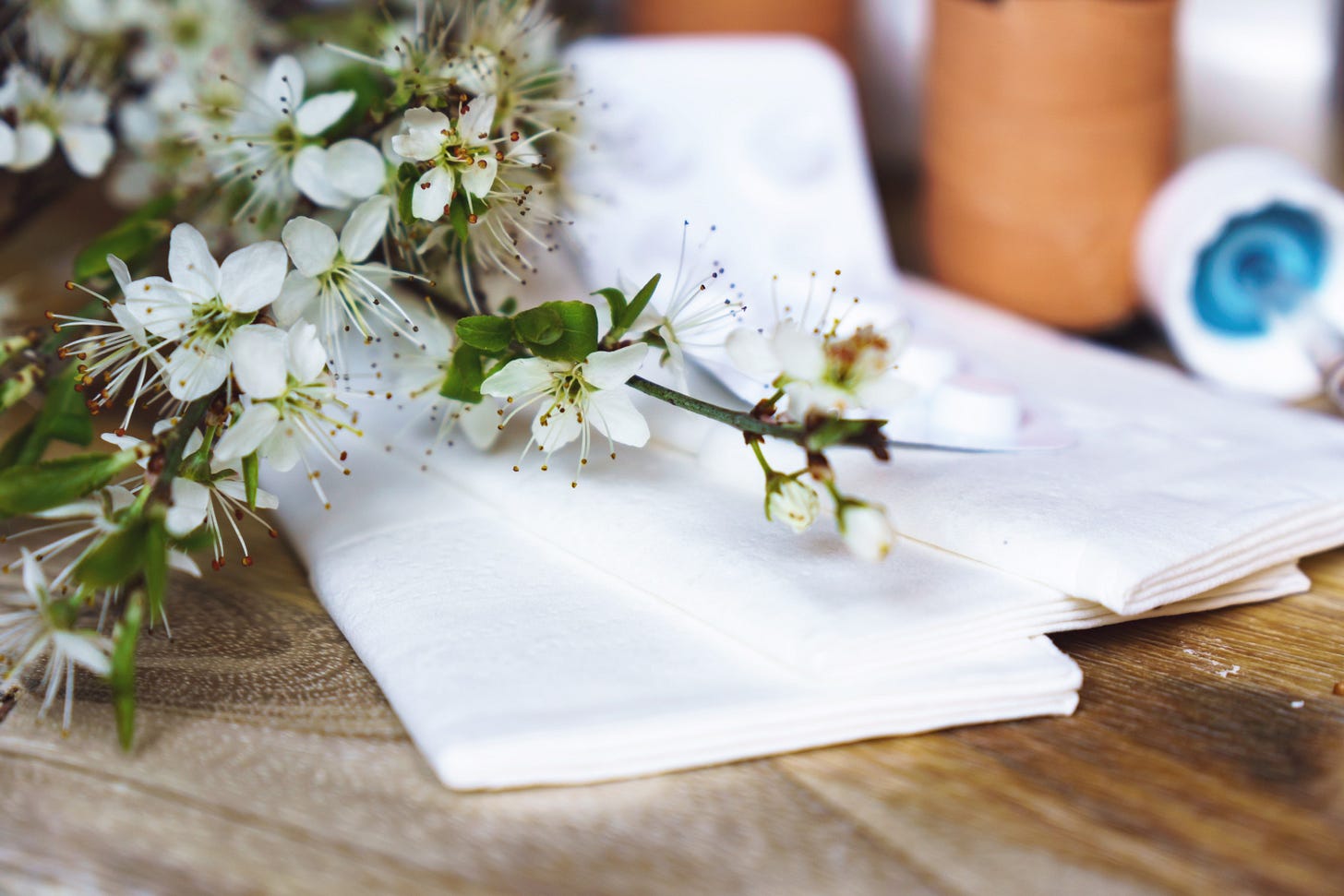 White flowers on folded white napkins, placed on a wooden table.