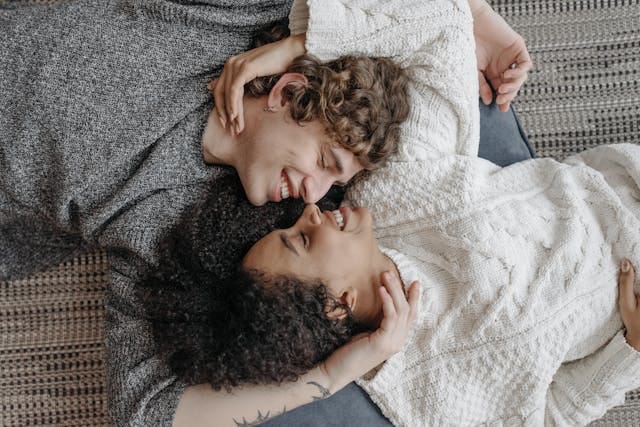 Couple lying on their backs smiling while they look into each other's eyes Couple lying on their backs smiling while they look into each other's eyes