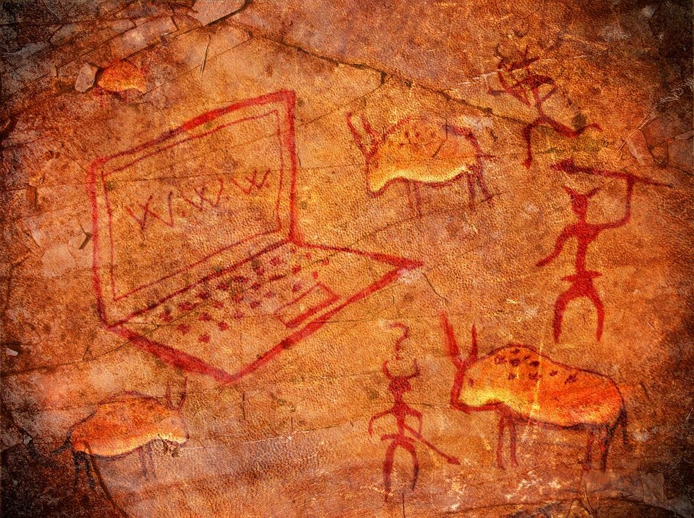 Humorous digital artwork depicting prehistoric cave paintings with a modern laptop computer among traditional animal figures.