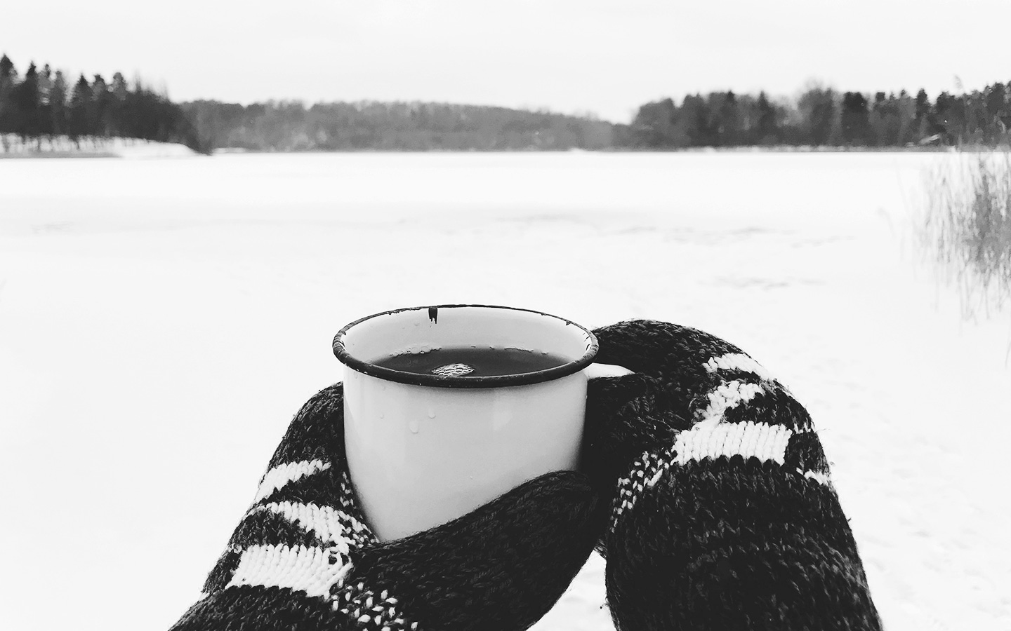 Hot tea with snowy background held in gloved hands