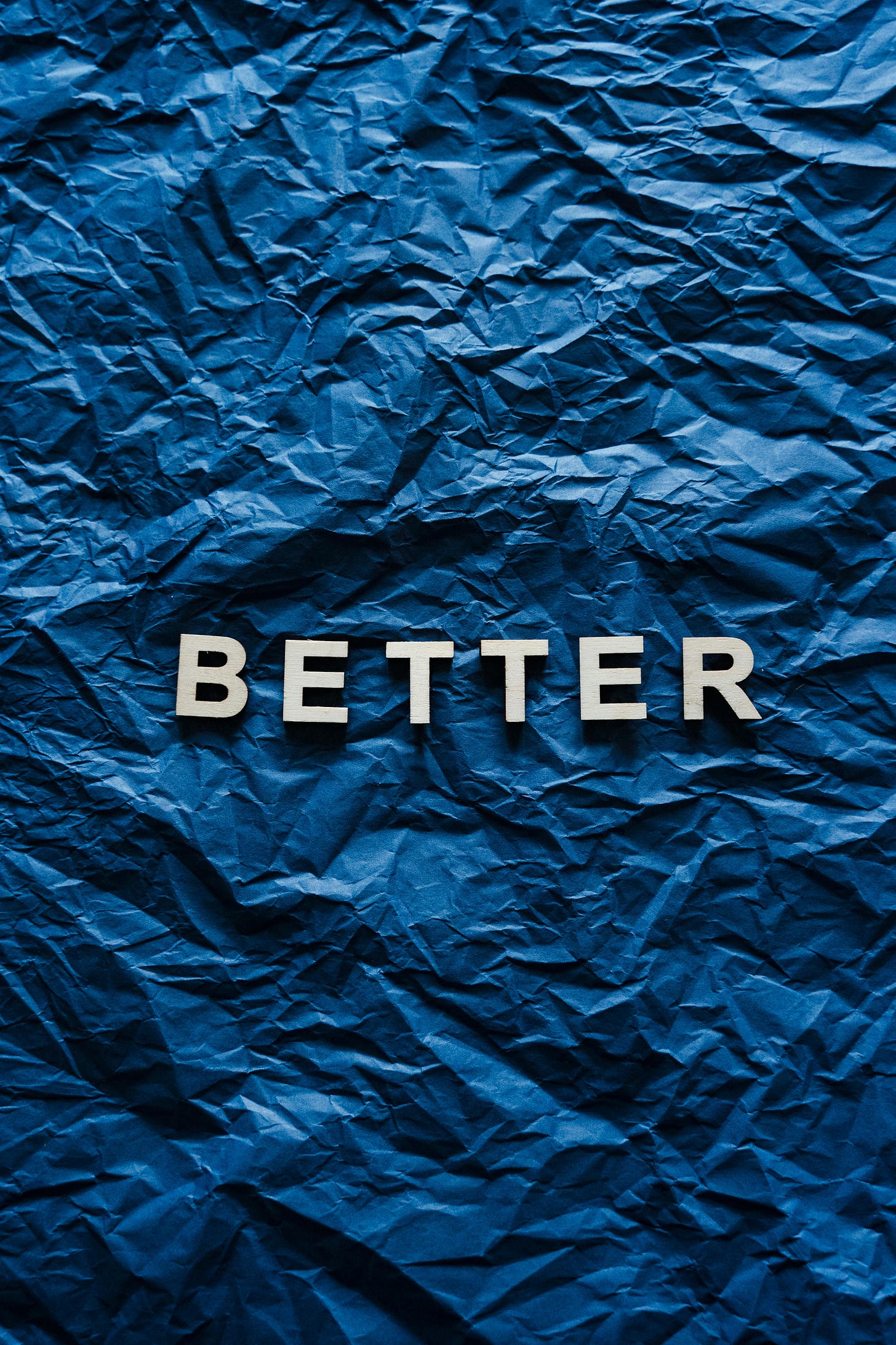 The word Better on a dark blue background of crinkled paper.