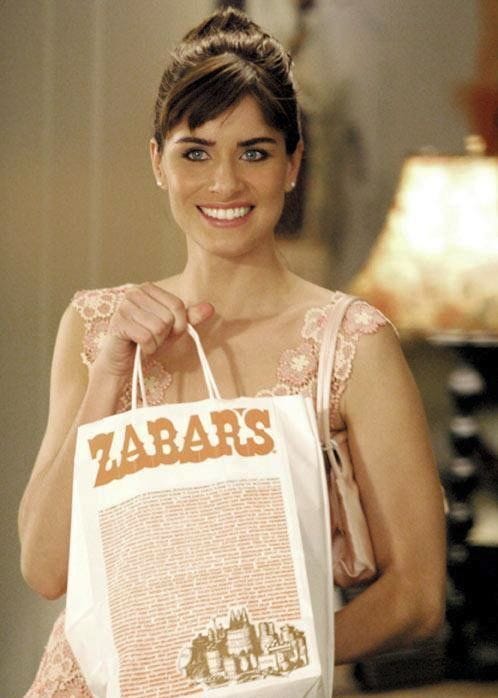 This may contain: a woman holding a shopping bag with the word zara's on it