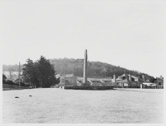 Black and white photo of Sueno's Stone, a tall carved cross slab, standing on grassy parkland with houses behind and a wooded hill behind that. Black and white photo of Sueno's Stone, a tall carved cross slab, standing on grassy parkland with houses behind and a wooded hill behind that.