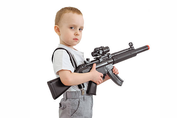 Boy with toy gun Boy with toy machine gun isolated on a white background. child holding toy gun stock pictures, royalty-free photos & images