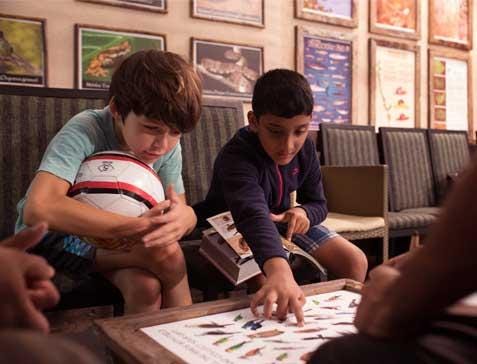 A group of boys playing a board game

Description automatically generated