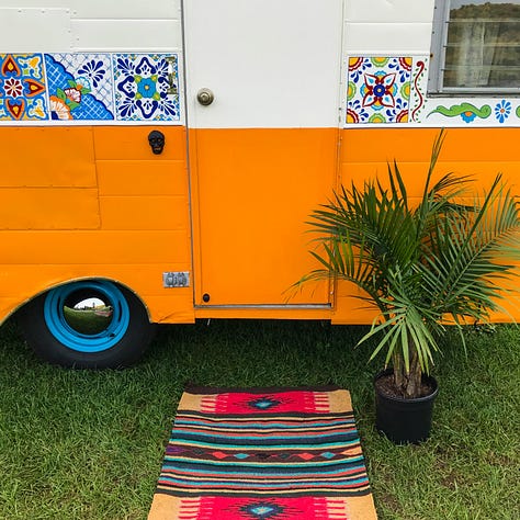 Vintage trailer painted orange turquoise and cream decorated with Mexican blankets and rugs