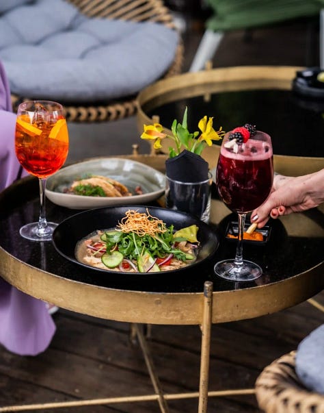 Dj tocando, comida servida en la mesa y vista de una de las terrazas bar en CDMX desde las alturas.